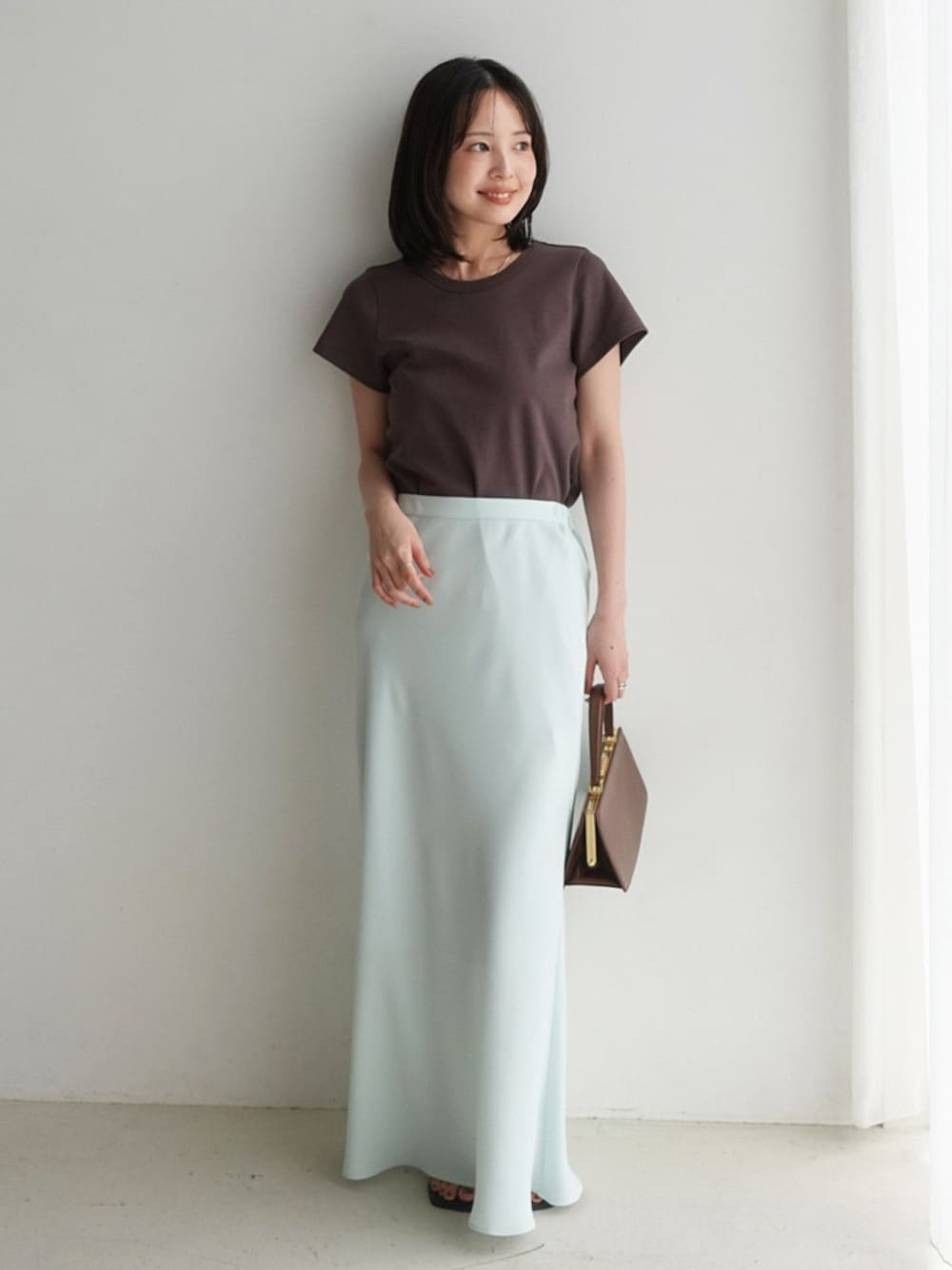 グリーン系のスカート、ブラウン系のTシャツ/カットソー、ブラウン系のサンダルを着用したレディースの夏コーディネートの1枚目の写真
