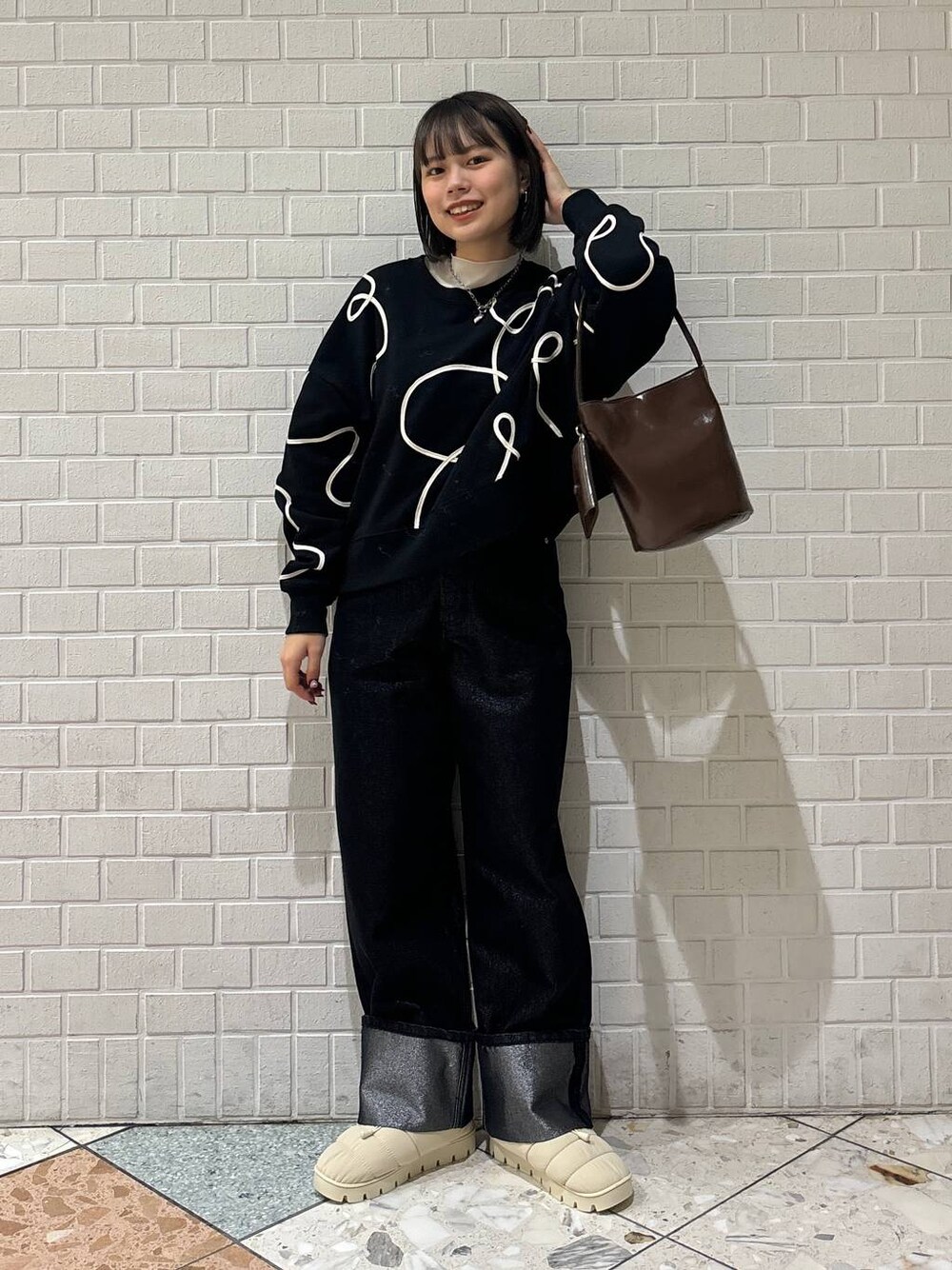 ブラック系のデニムパンツ、ホワイト系のブーツ、ブラック系のスウェットを着用したレディースの冬コーディネートの1枚目の写真