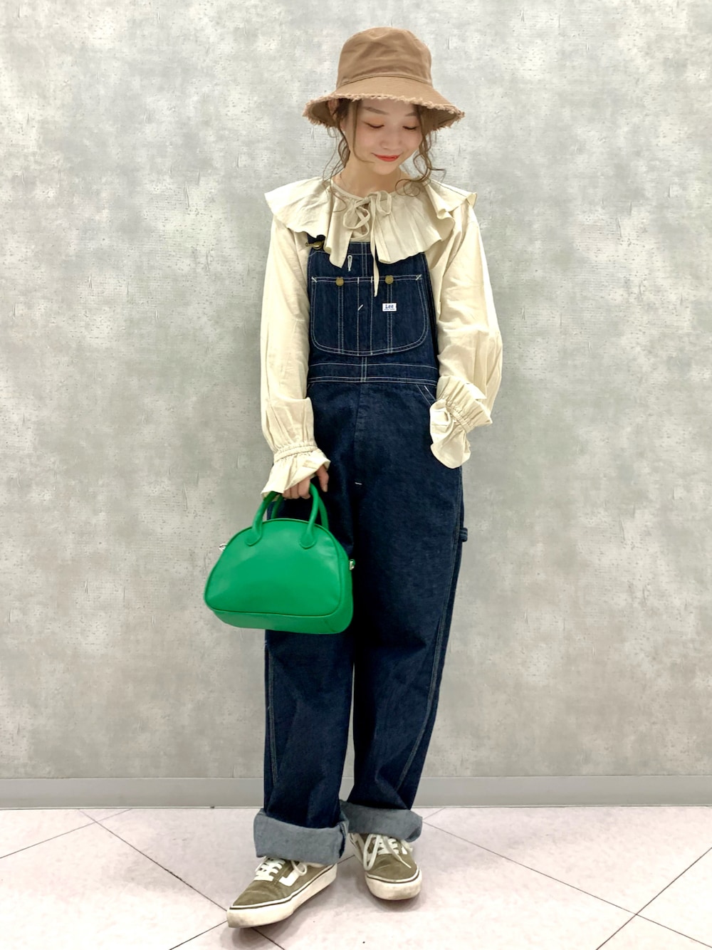 ブルー系のサロペット/オーバーオール、グリーン系のバッグ、グリーン系のスニーカーを着用したレディースの春コーディネートの1枚目の写真