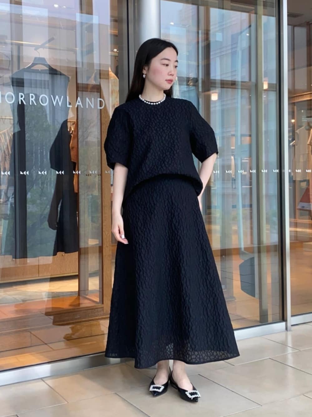 ブラック系のパンプス、ブラック系のシャツ/ブラウス、ブラック系のスカートを着用したレディースの春コーディネートの1枚目の写真