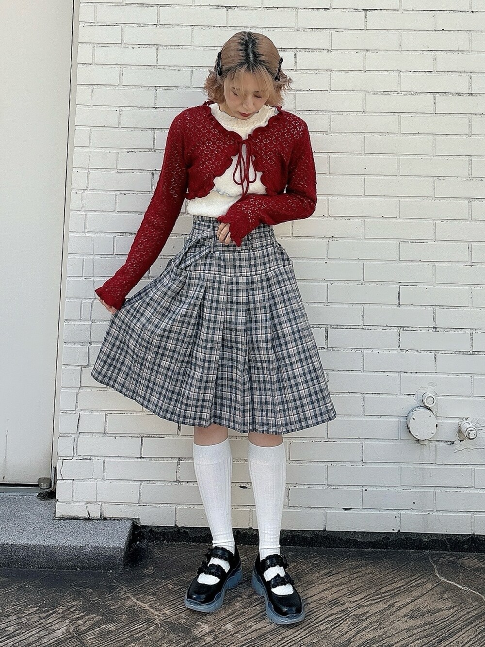 ブラウン系のスカート、ブラック系のスニーカー、ホワイト系のTシャツ/カットソーを着用したレディースの春コーディネートの1枚目の写真