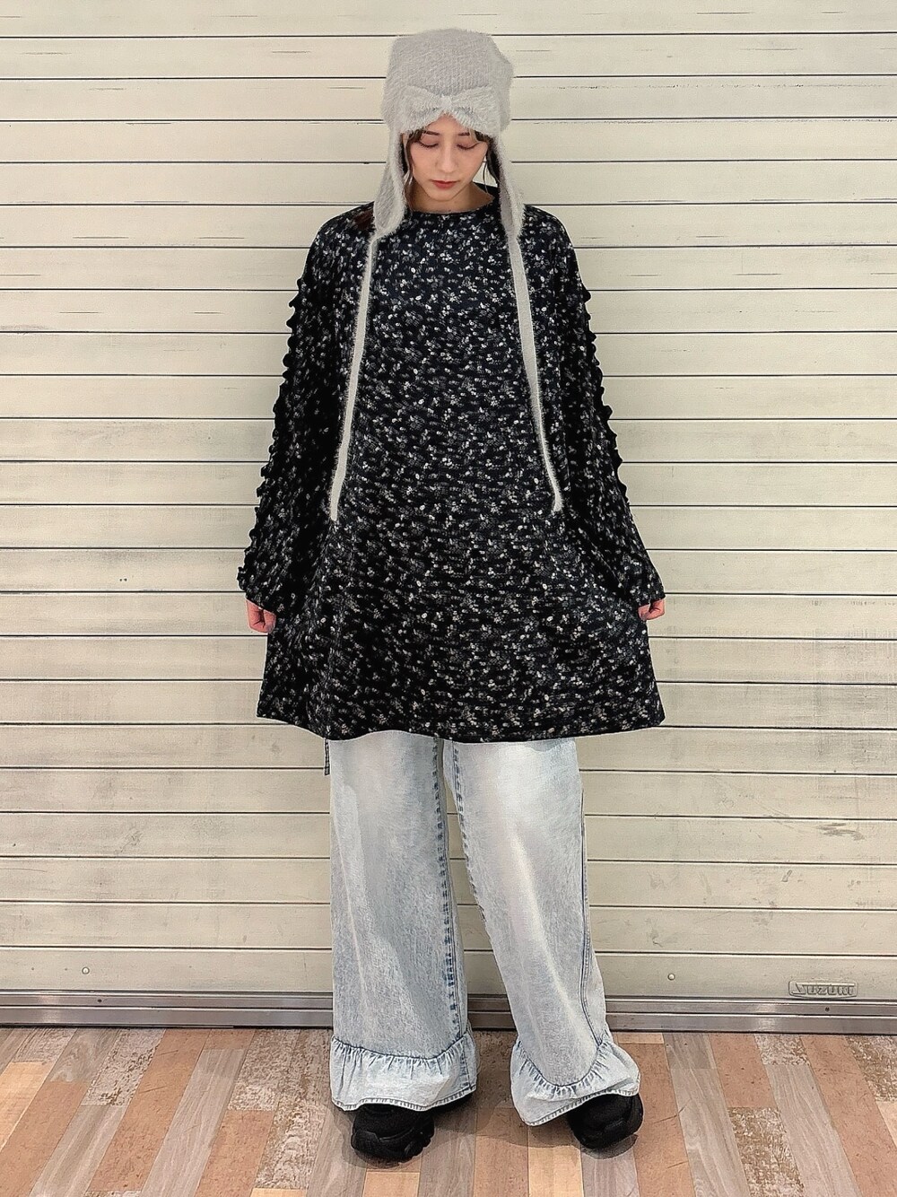 ブラック系のワンピース、ブルー系のデニムパンツ、ブラック系のスニーカーを着用したレディースの秋コーディネートの1枚目の写真