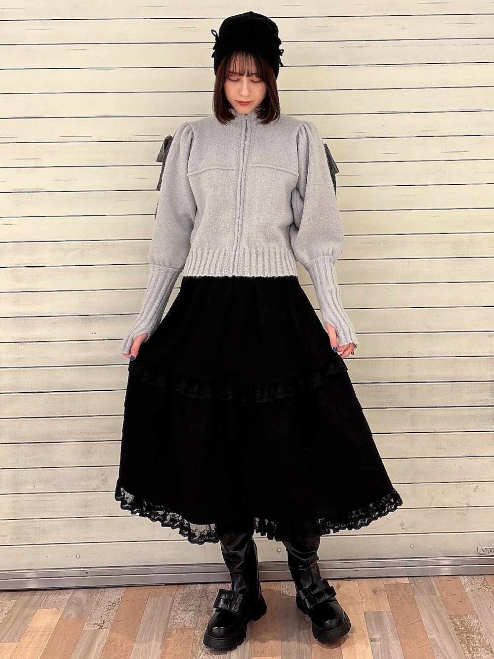グレー系のカーディガン/ボレロ、ブラック系のスカート、ブラック系のブーツを着用したレディースの冬コーディネートの1枚目の写真