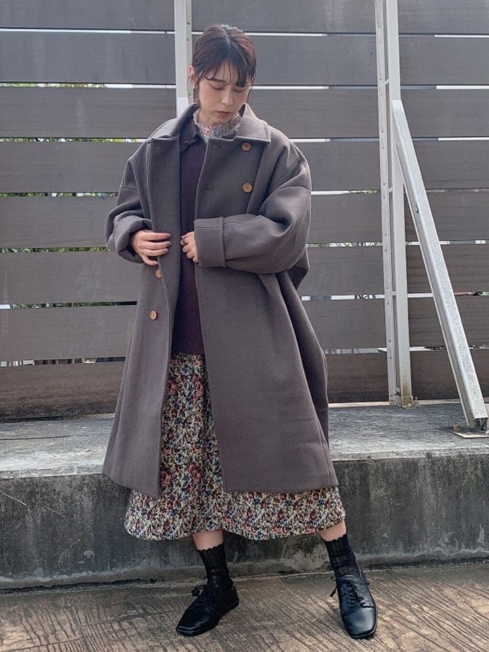 ブラウン系のニット/セーター、グリーン系のチェスターコート、レッド系のスカートを着用したレディースの秋コーディネートの1枚目の写真