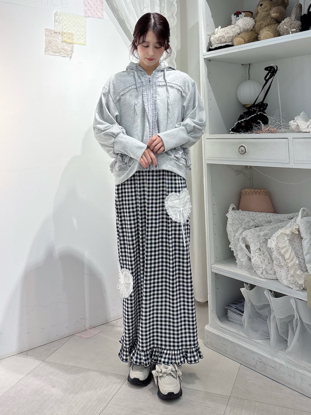 グレー系のパーカー、ブラック系のスカート、ホワイト系のスニーカーを着用したレディースの秋コーディネートの1枚目の写真