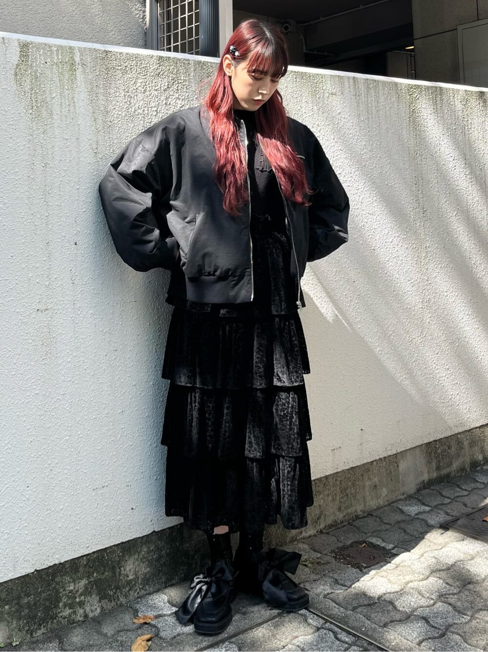 ブラック系のニット/セーター、ブラック系のスカート、ブラック系のモカシン/デッキシューズを着用したレディースの秋コーディネートの1枚目の写真