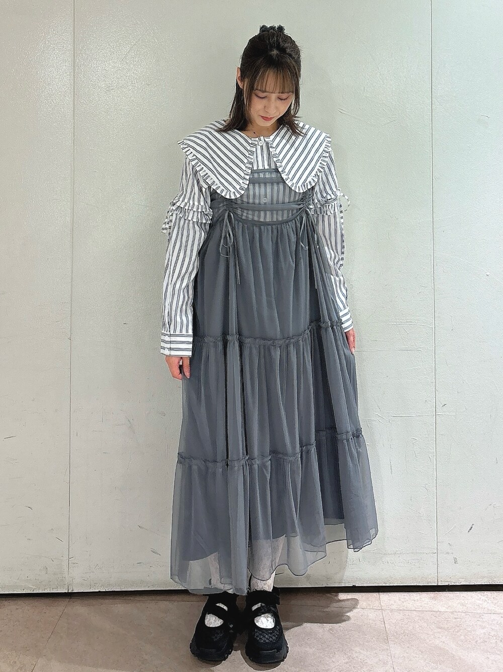 グレー系のワンピース、ホワイト系のシャツ/ブラウス、ブラック系のスニーカーを着用したレディースの夏コーディネートの1枚目の写真