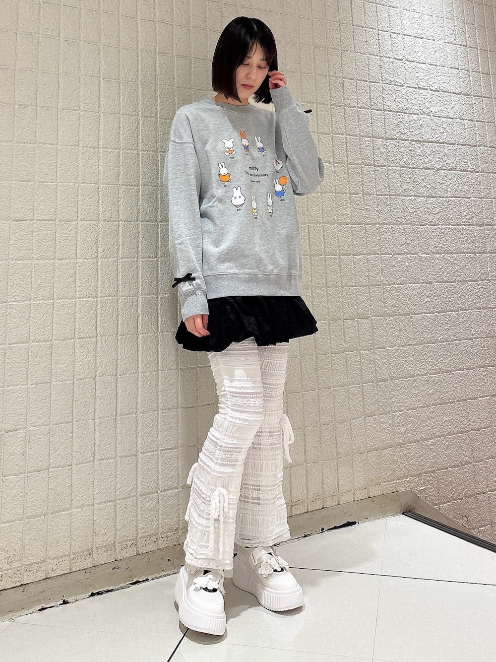 グレー系のスウェット、ブラック系のスカート、ホワイト系のその他パンツを着用したレディースの冬コーディネートの1枚目の写真