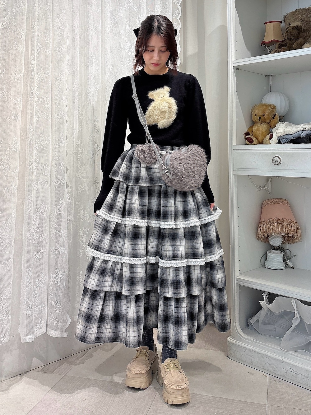 ブラック系のニット/セーター、ブラック系のスカート、グレー系のショルダーバッグを着用したレディースの秋コーディネートの1枚目の写真