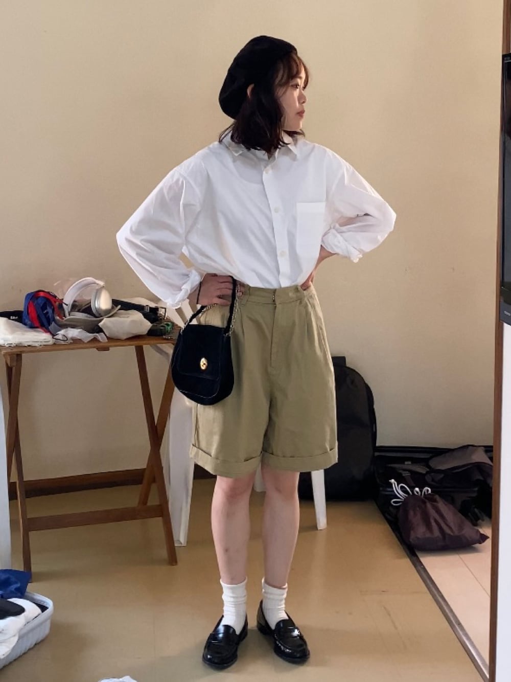 ブラック系のローファー、ベージュ系のチノパンツ、ブラック系のショルダーバッグを着用したレディースの春コーディネートの1枚目の写真