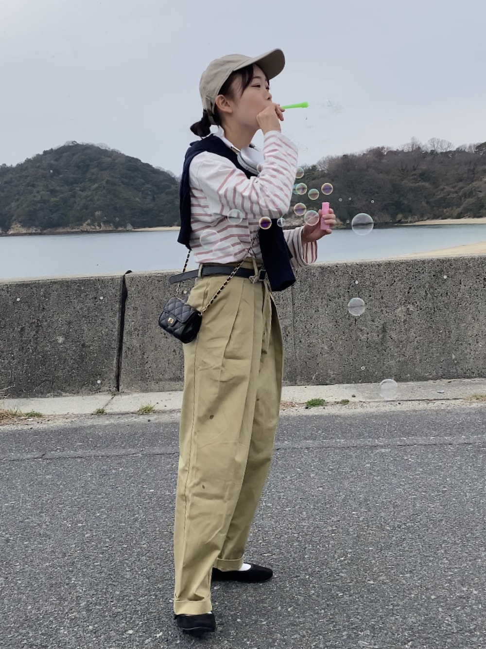 ベージュ系のチノパンツ、ピンク系のTシャツ/カットソー、ブラック系のトートバッグを着用したレディースの春コーディネートの1枚目の写真