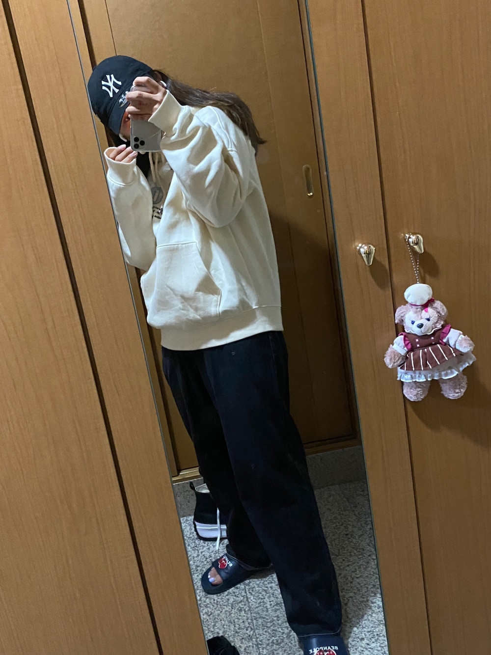 ブラック系のデニムパンツ、ホワイト系のパーカー、ブラック系のキャップを着用したレディースの冬コーディネートの1枚目の写真