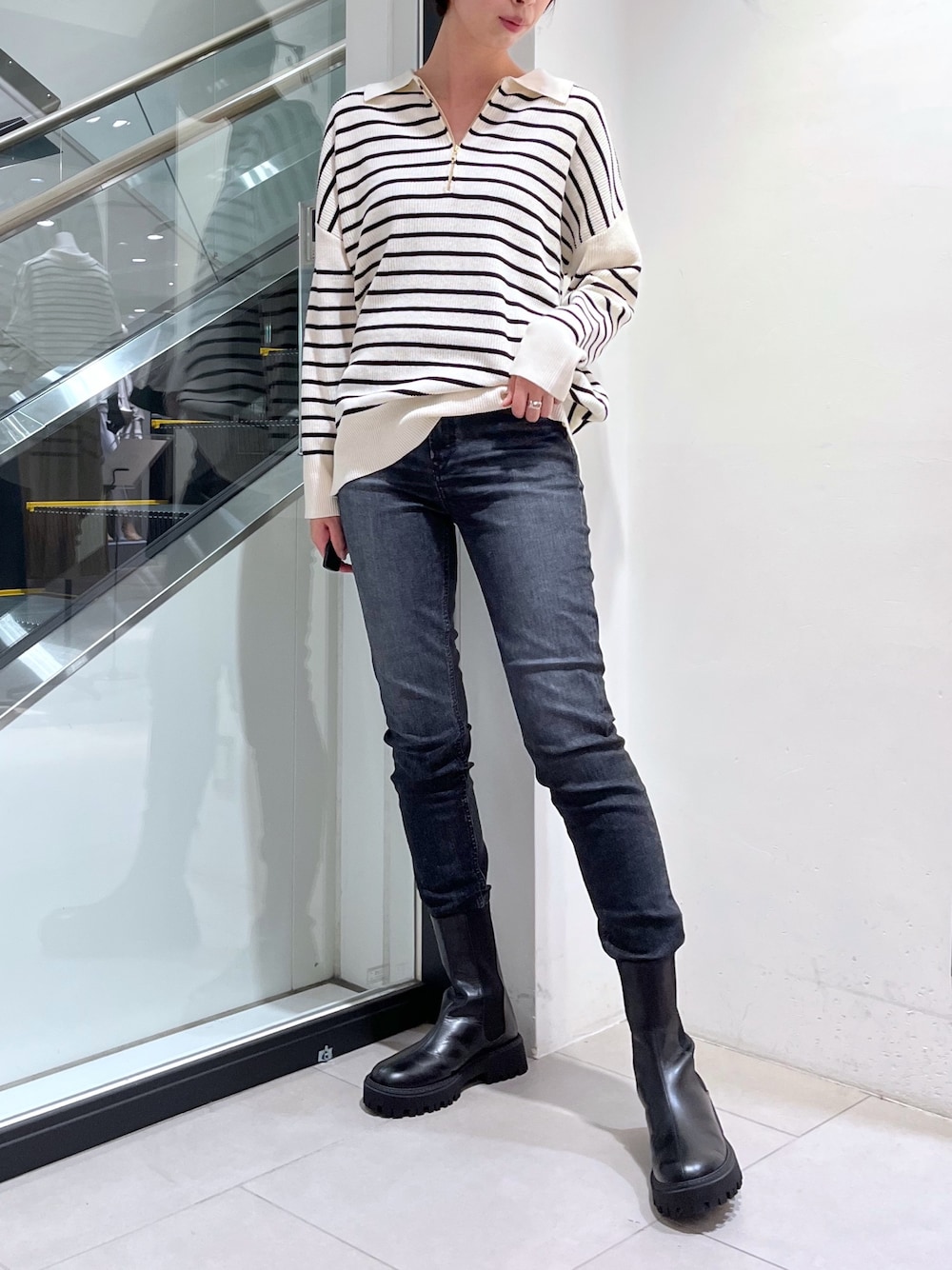 ブラック系のデニムパンツ、ホワイト系のニット/セーター、ブラック系のその他シューズを着用したレディースの秋コーディネートの1枚目の写真