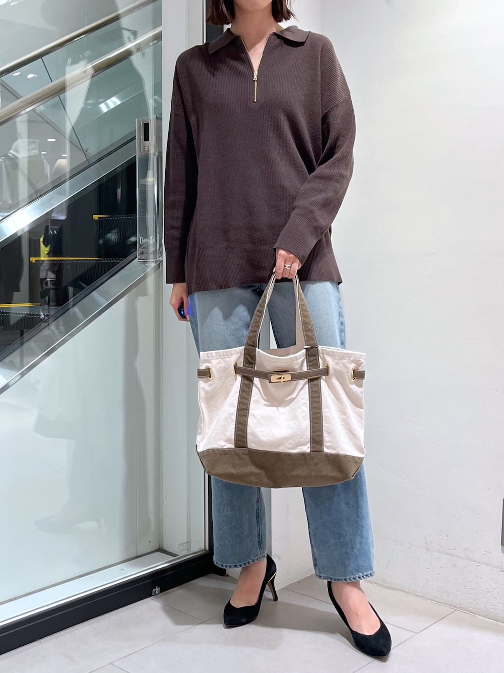 ベージュ系のバッグ、ブルー系のデニムパンツ、ブラウン系のニット/セーターを着用したレディースの秋コーディネートの1枚目の写真