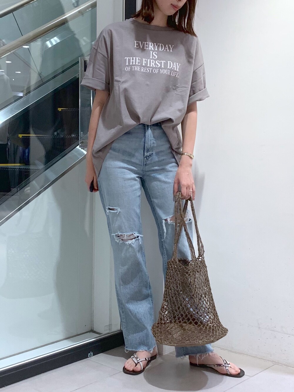 ブルー系のデニムパンツ、ベージュ系のTシャツ/カットソー、ブラウン系のショルダーバッグを着用したレディースの夏コーディネートの1枚目の写真