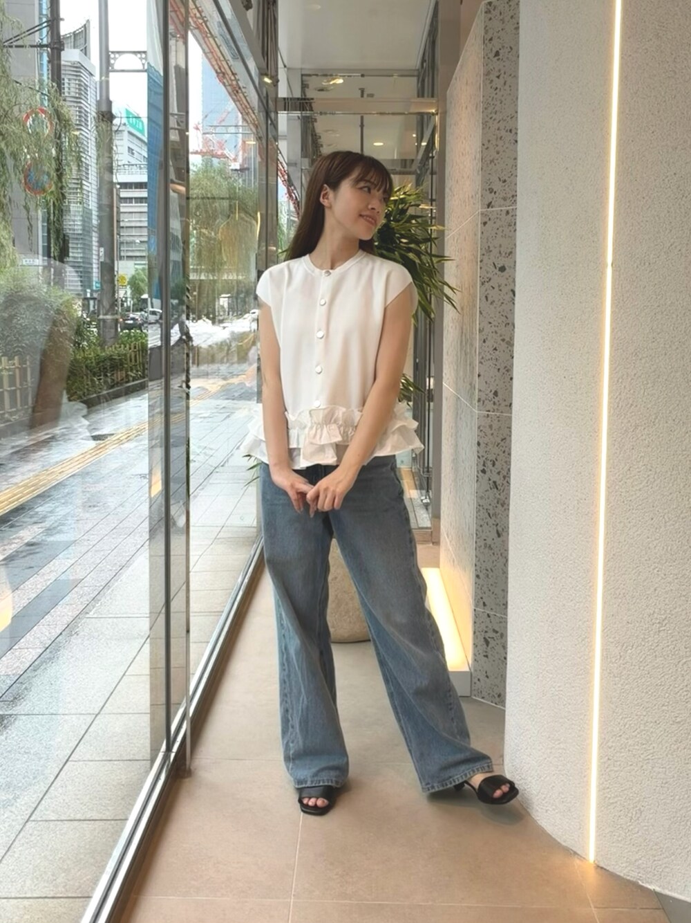 ホワイト系のベスト、ブルー系のデニムパンツ、ブラック系のサンダルを着用したレディースの夏コーディネートの1枚目の写真