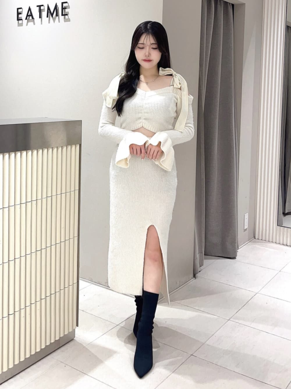 ホワイト系のワンピース、ブラック系のブーツを着用したレディースの冬コーディネートの1枚目の写真