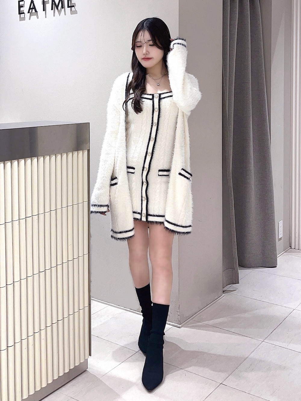 ホワイト系のワンピース、ブラック系のブーツを着用したレディースの冬コーディネートの1枚目の写真