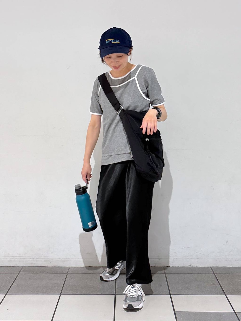 ブラック系のスカート、ブラック系のショルダーバッグ、グレー系のTシャツ/カットソーを着用したレディースの春コーディネートの1枚目の写真