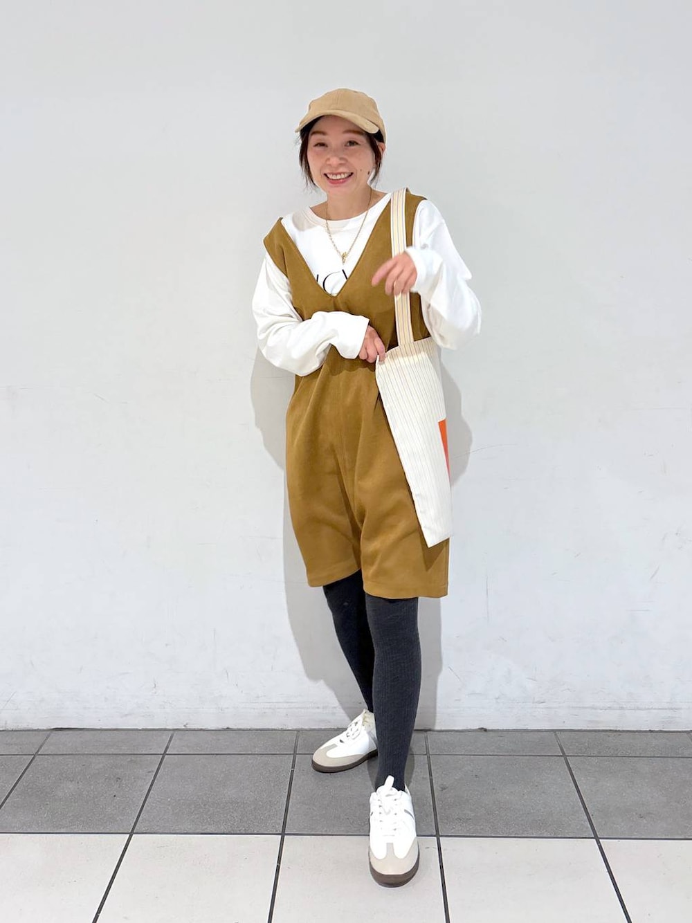 イエロー系のトートバッグ、ホワイト系のTシャツ/カットソー、ホワイト系のスニーカーを着用したレディースの冬コーディネートの1枚目の写真