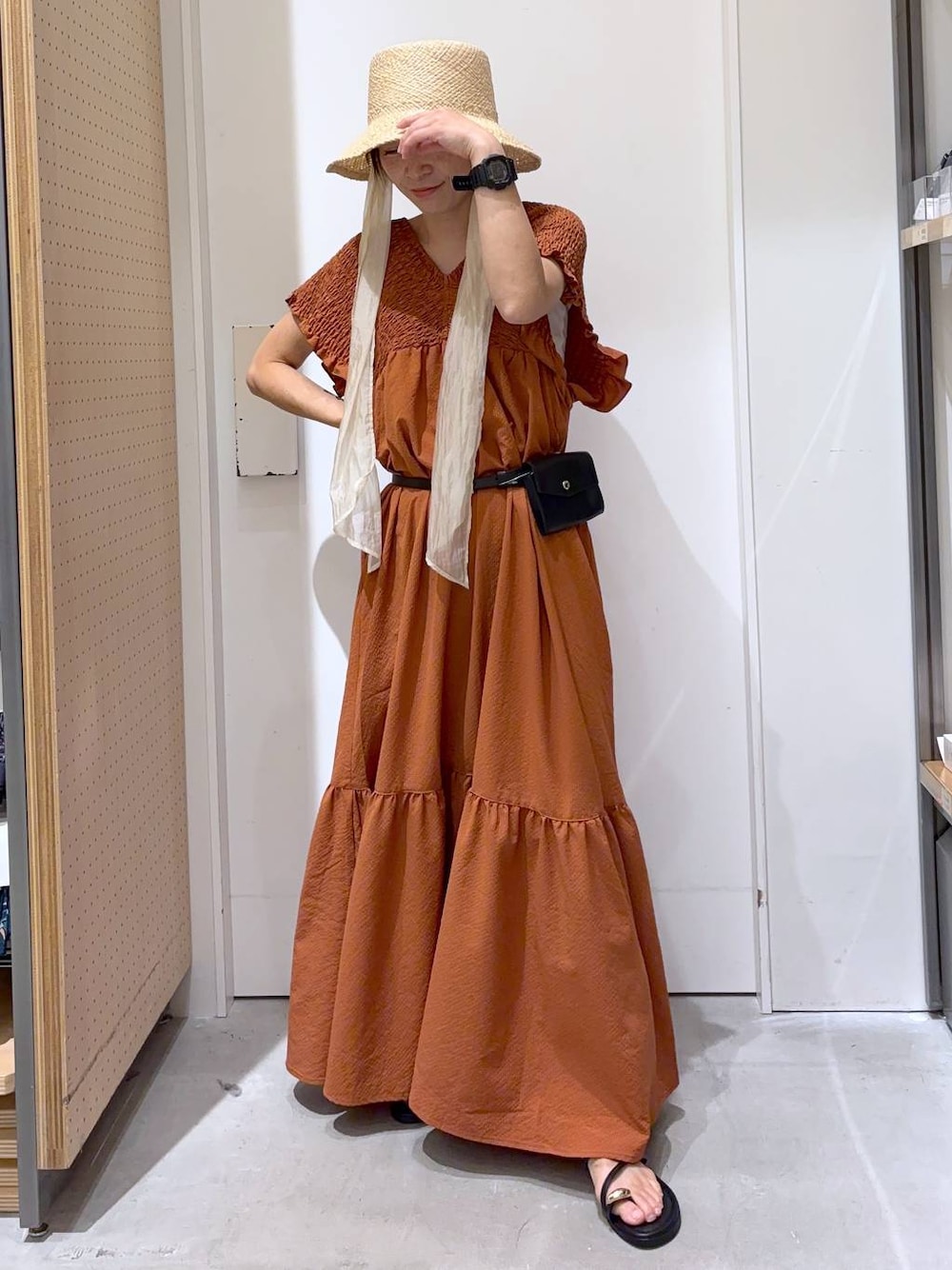 オレンジ系のワンピース、ブラック系のサンダル、ホワイト系のキャミソールを着用したレディースの夏コーディネートの1枚目の写真