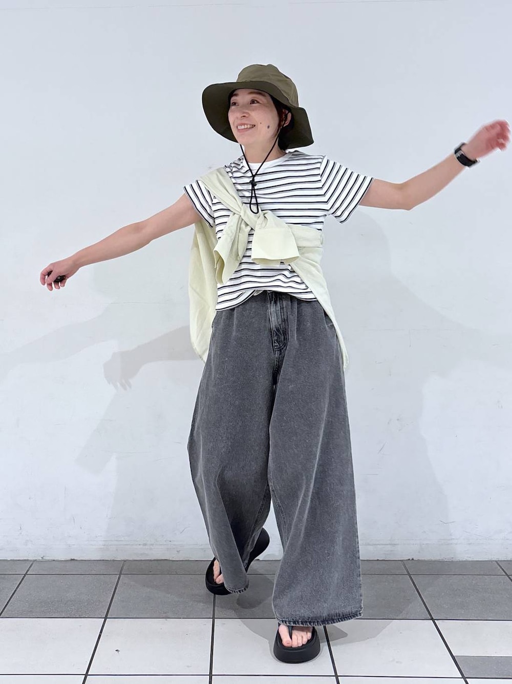ブラック系のデニムパンツ、ブラック系のサンダルを着用したレディースの春コーディネートの1枚目の写真