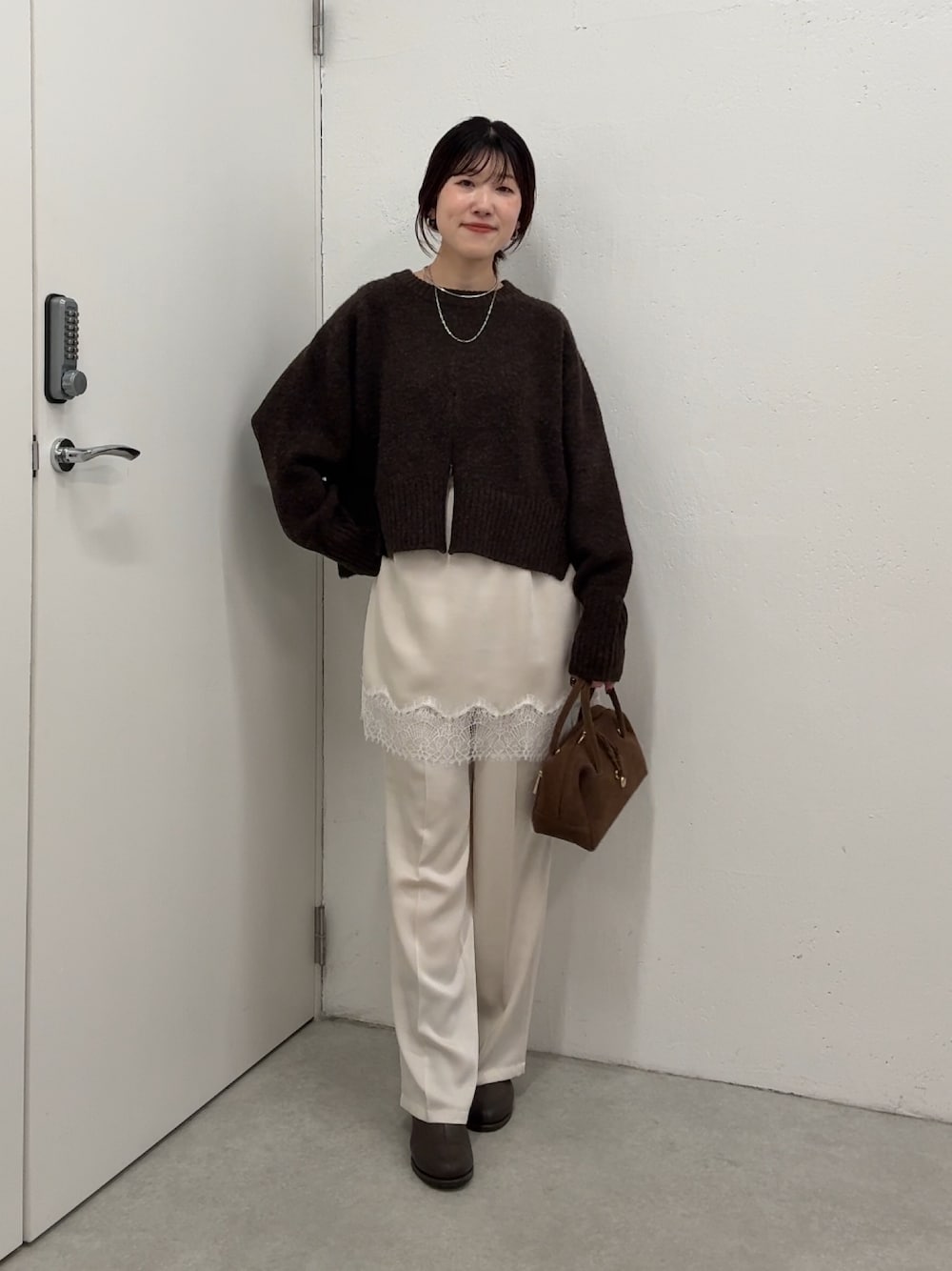 ブラウン系のニット/セーター、ホワイト系のその他パンツ、ブラウン系のボストンバッグを着用したレディースの秋コーディネートの1枚目の写真