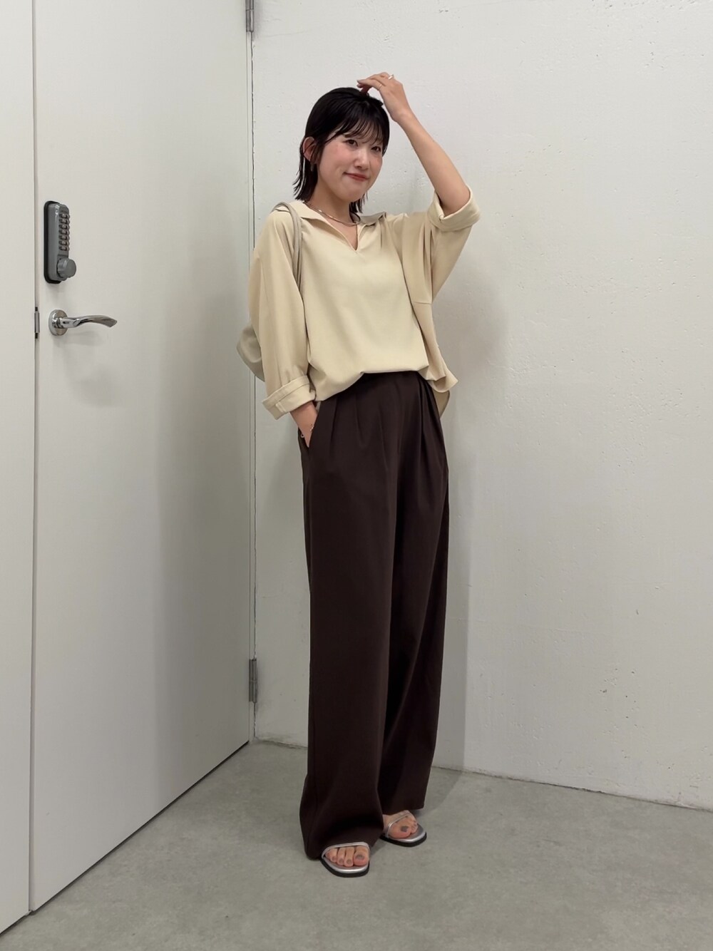 イエロー系のシャツ/ブラウス、ブラウン系のスラックス、ホワイト系のショルダーバッグを着用したレディースの春コーディネートの1枚目の写真
