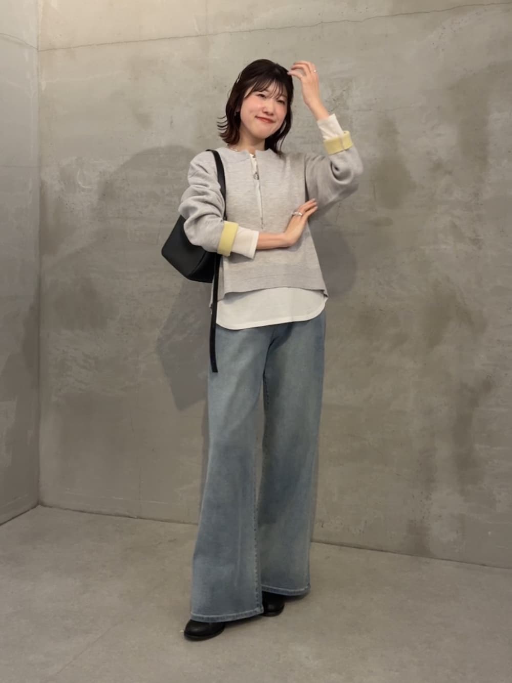 グレー系のニット/セーター、ホワイト系のTシャツ/カットソー、ブルー系のデニムパンツを着用したレディースの冬コーディネートの1枚目の写真