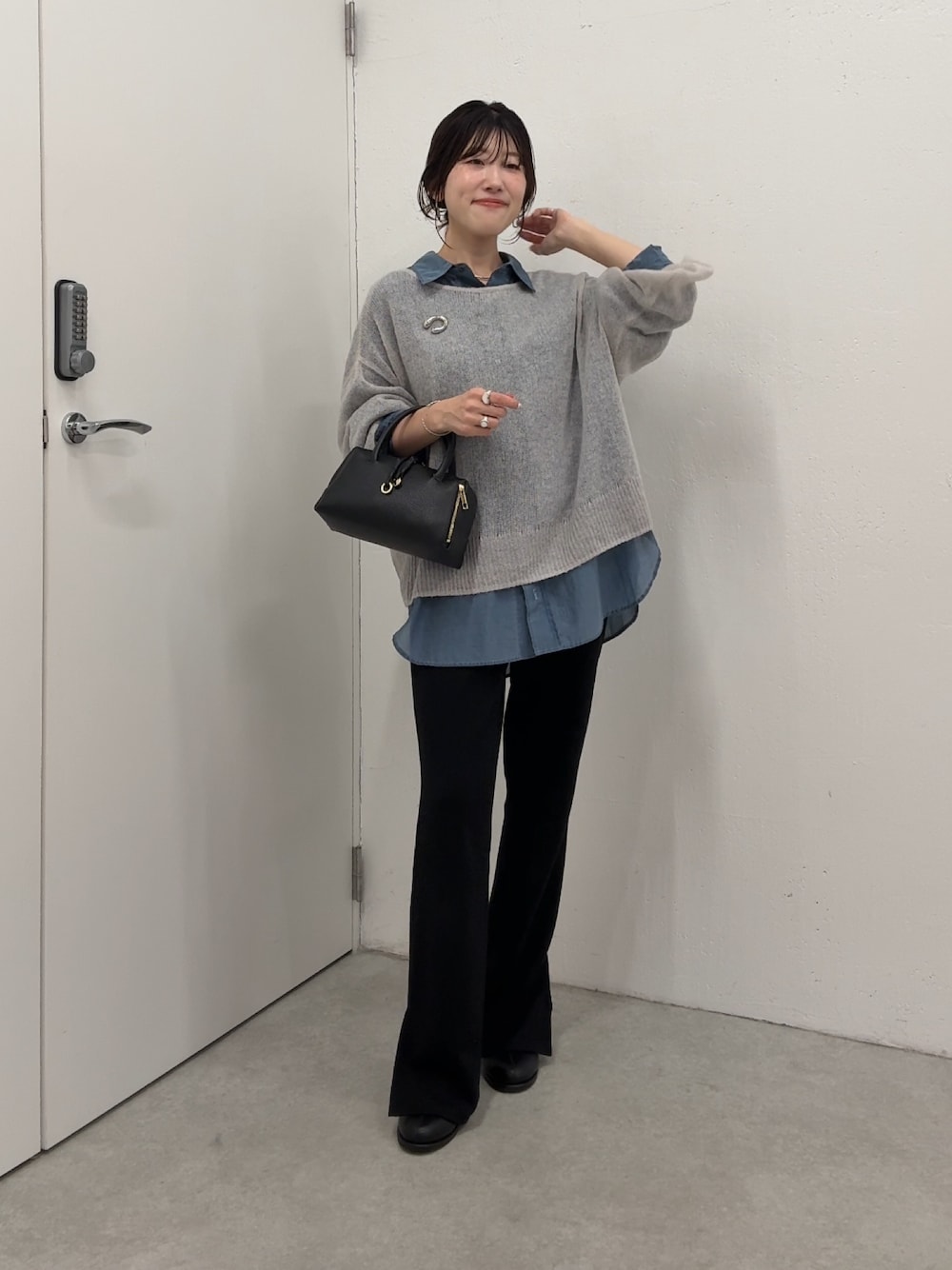 グレー系のニット/セーター、ブルー系のシャツ/ブラウス、ブラック系のボストンバッグを着用したレディースの秋コーディネートの1枚目の写真