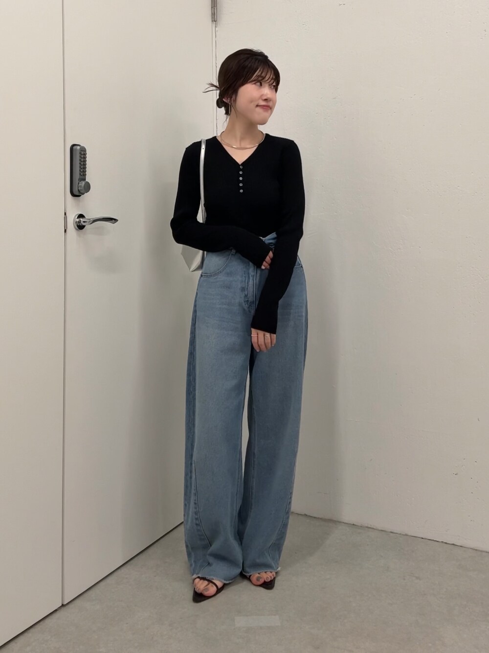ブラック系のニット/セーター、ブルー系のデニムパンツ、シルバー系のショルダーバッグを着用したレディースの夏コーディネートの1枚目の写真