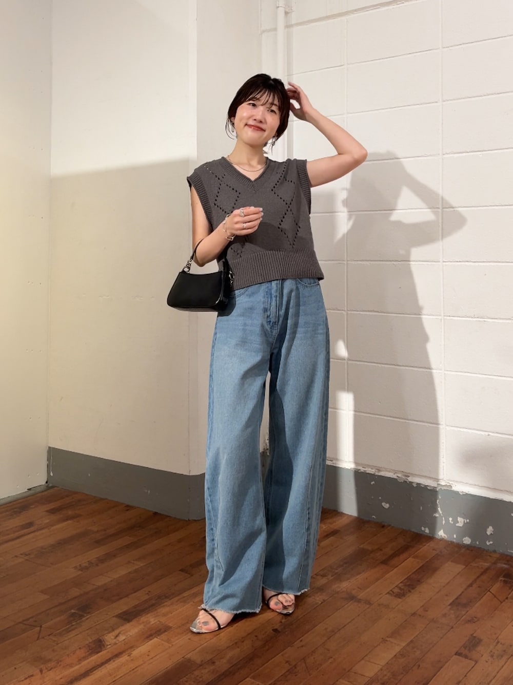 グレー系のニット/セーター、ブルー系のデニムパンツ、ブラック系のショルダーバッグを着用したレディースの夏コーディネートの1枚目の写真