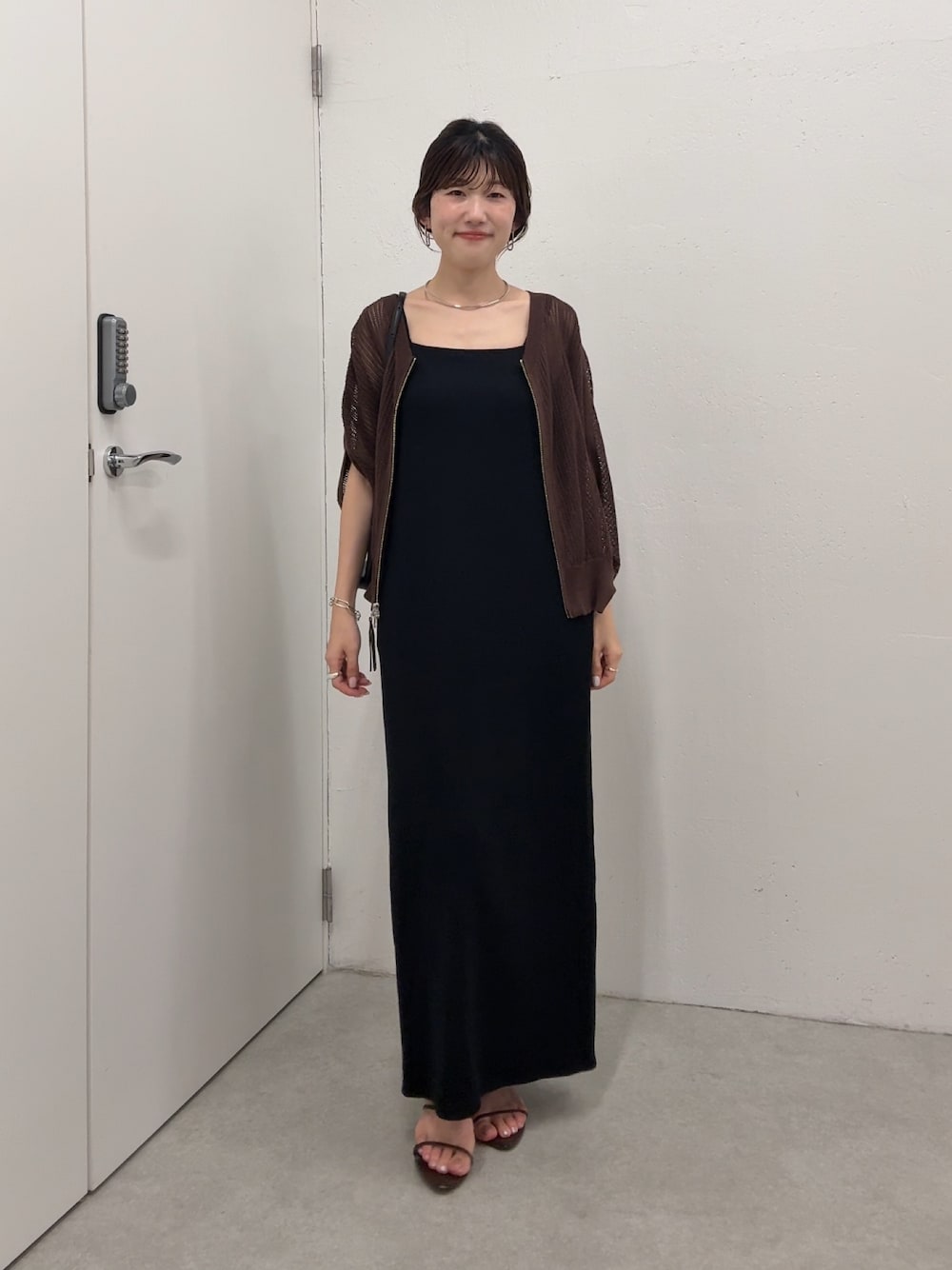 ブラック系のワンピース、ブラウン系のカーディガン/ボレロ、ゴールド系のネックレスを着用したレディースの夏コーディネートの1枚目の写真