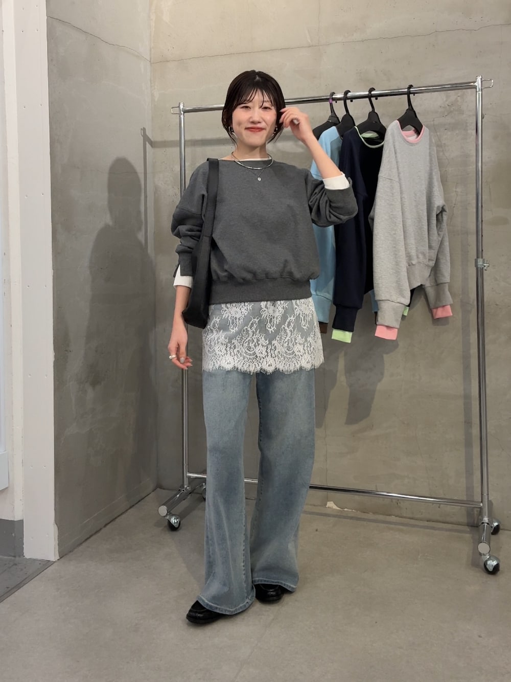 グレー系のスウェット、ホワイト系のスカート、ブルー系のデニムパンツを着用したレディースの春コーディネートの1枚目の写真