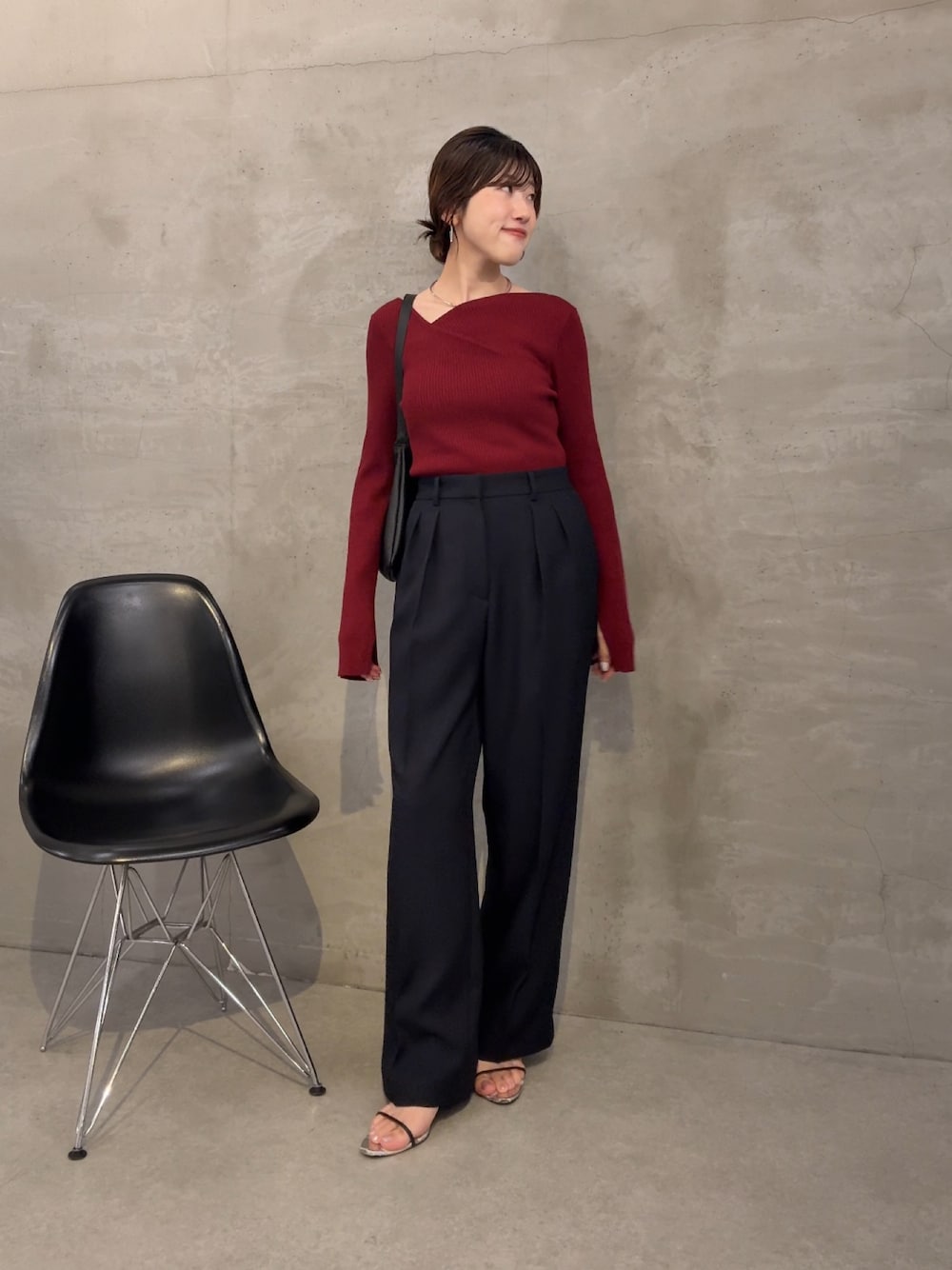 レッド系のニット/セーター、ブルー系のスラックス、ブラック系のショルダーバッグを着用したレディースの夏コーディネートの1枚目の写真