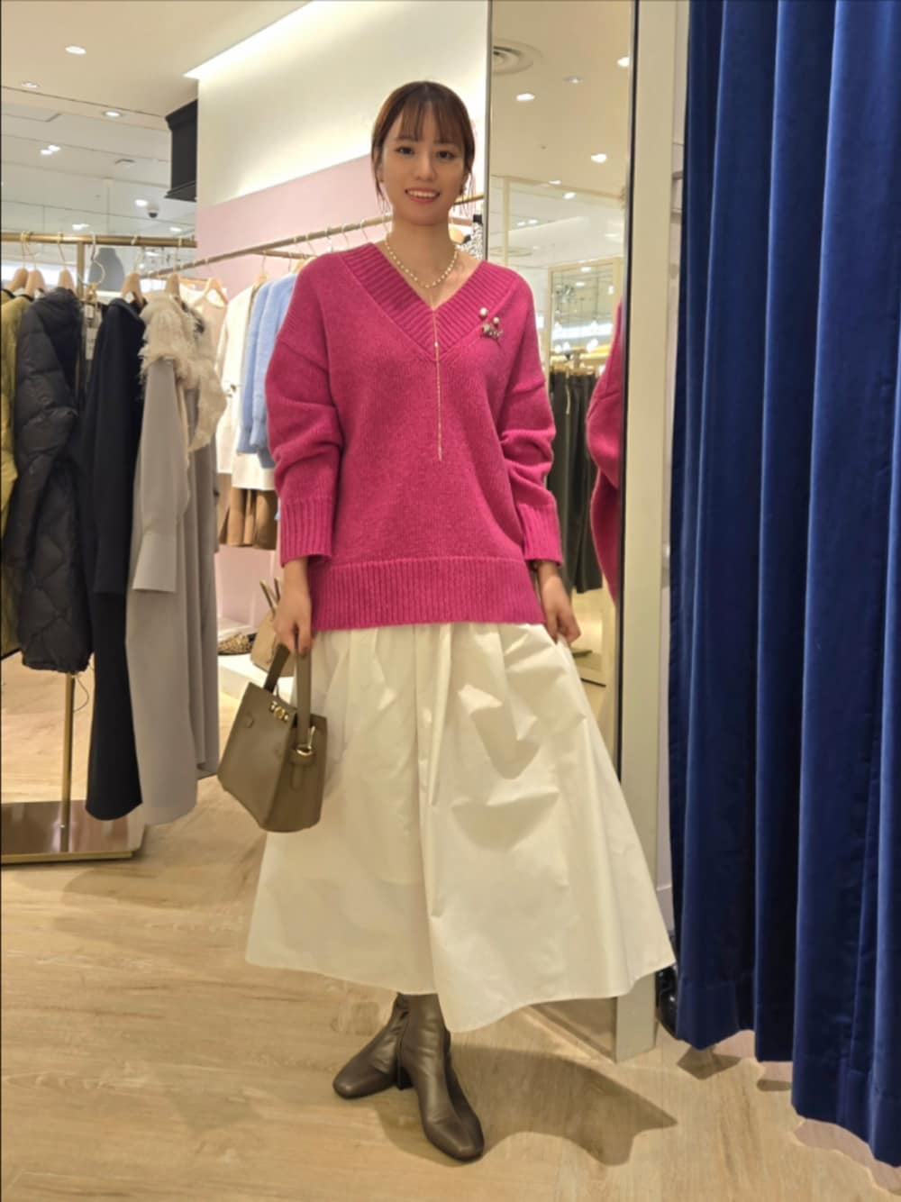 ホワイト系のスカート、ベージュ系のショルダーバッグ、ピンク系のニット/セーターを着用したレディースの秋コーディネートの1枚目の写真