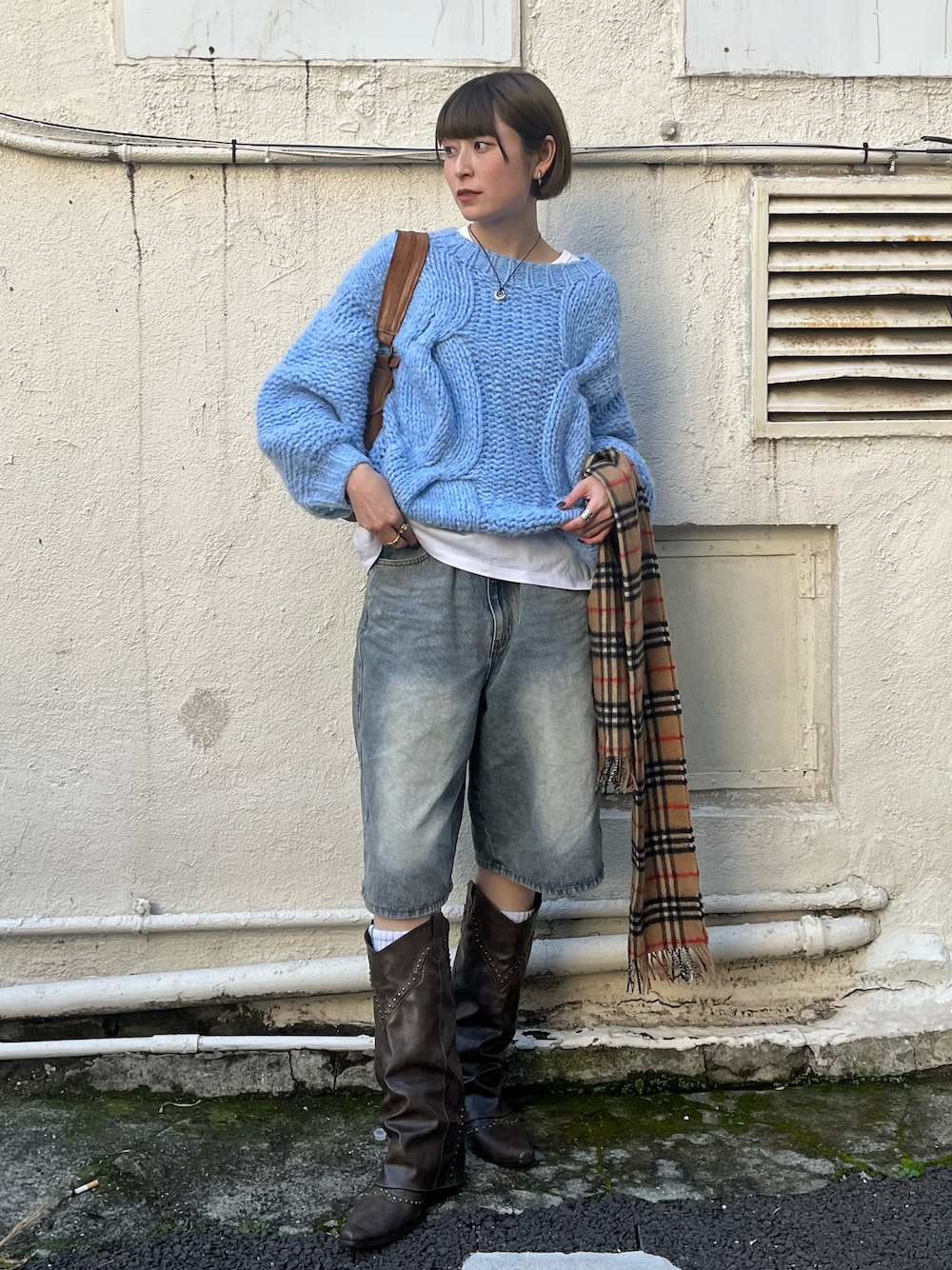 ブルー系のデニムパンツ、ブルー系のニット/セーター、ブラウン系のハンドバッグを着用したレディースの秋コーディネートの1枚目の写真