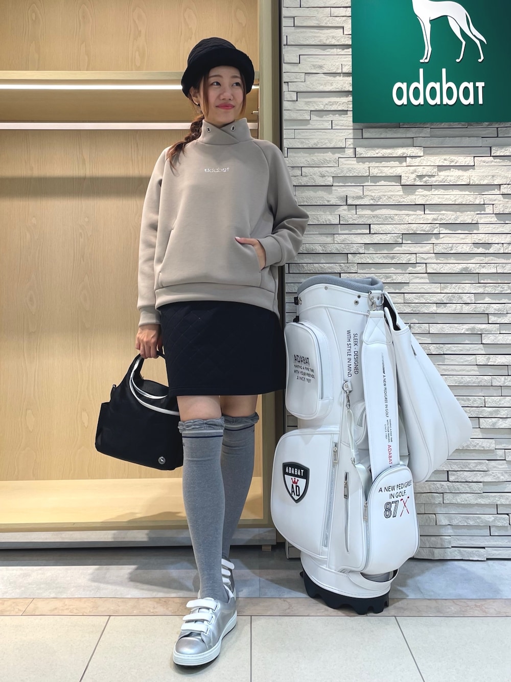 ベージュ系のTシャツ/カットソー、ブラック系のスカート、ブラック系のハンドバッグを着用したレディースの秋コーディネートの1枚目の写真