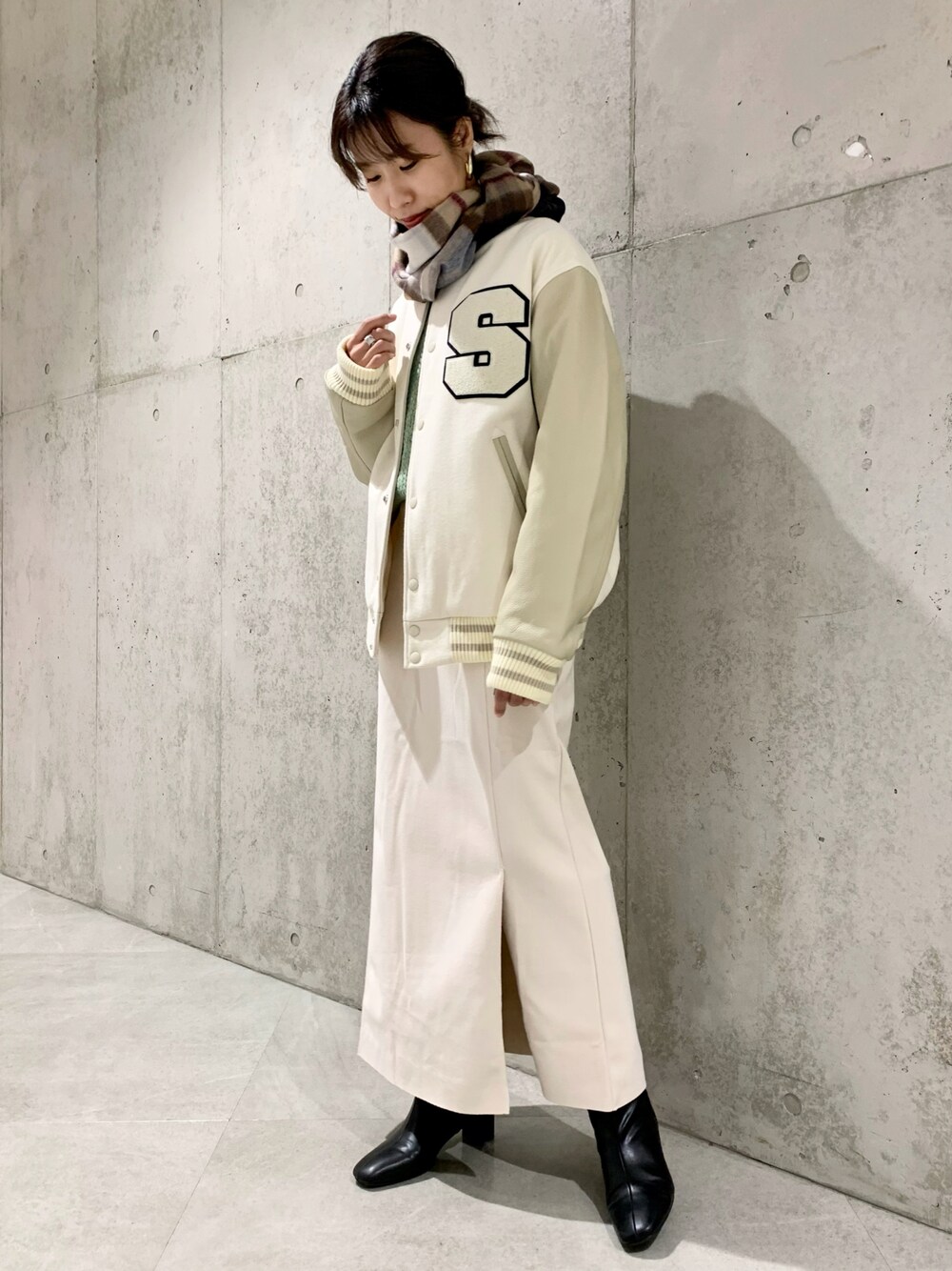 ホワイト系のスタジャン、ホワイト系のスカート、グリーン系のニット/セーターを着用したレディースの秋コーディネートの1枚目の写真