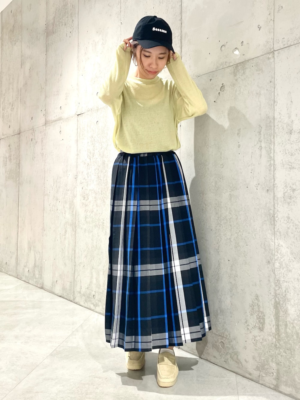 ブラック系のスカート、イエロー系のTシャツ/カットソー、ブラック系のキャップを着用したレディースの秋コーディネートの1枚目の写真