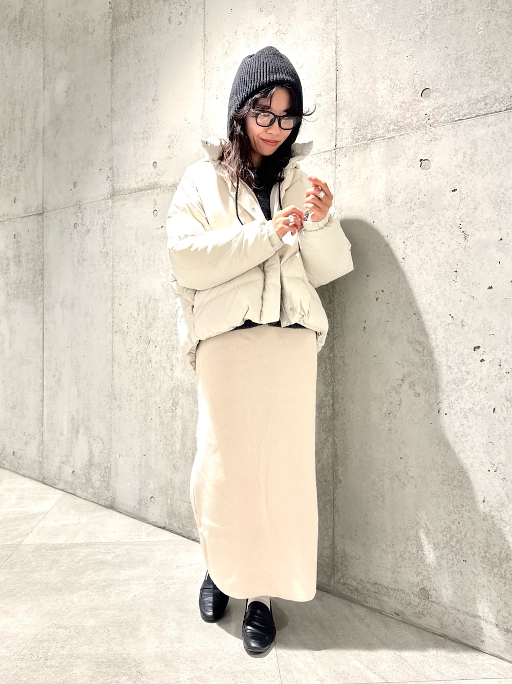 ホワイト系のスカート、グリーン系のニット/セーター、ホワイト系のダウンジャケット/コートを着用したレディースの秋コーディネートの1枚目の写真
