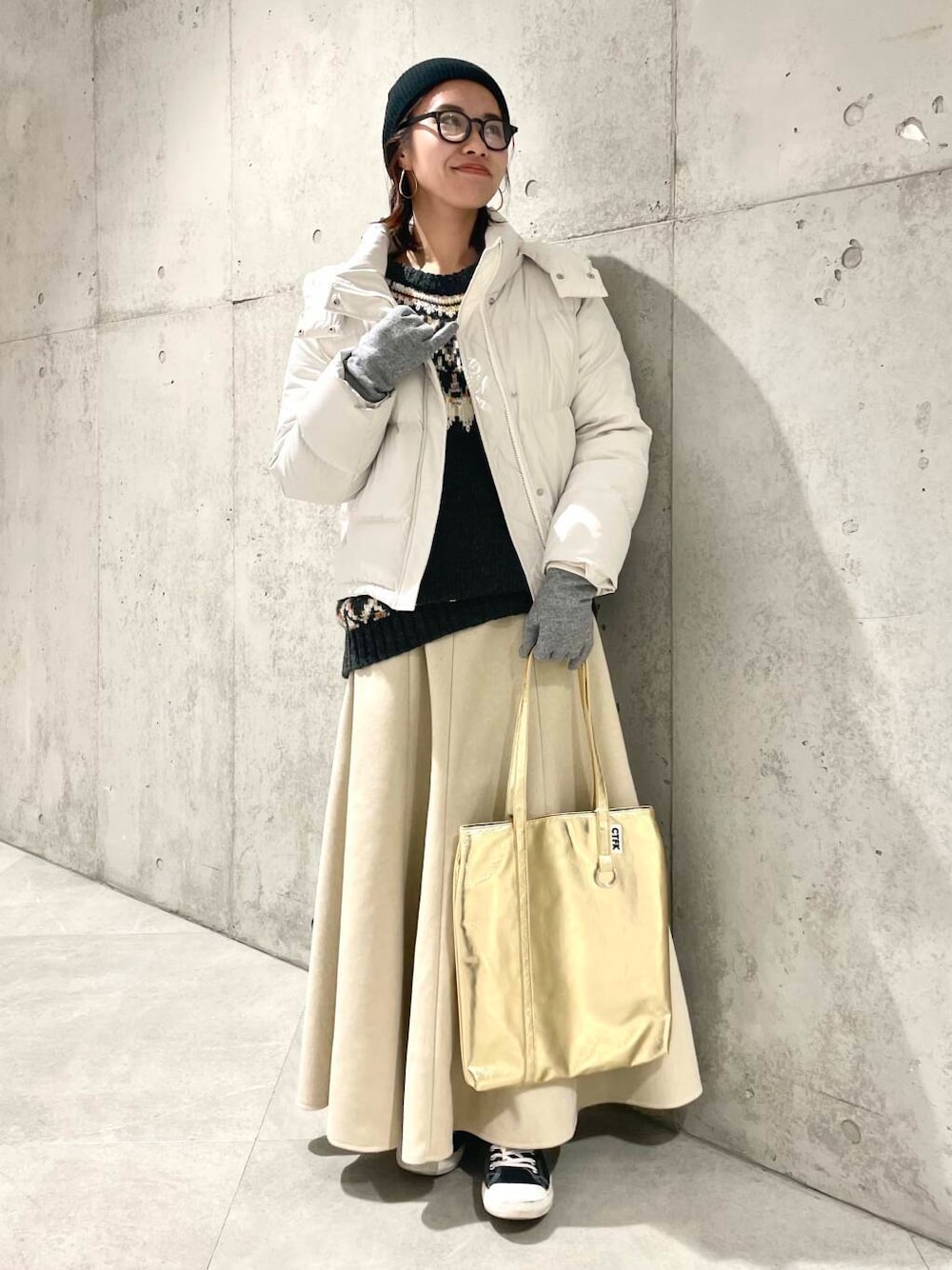 ホワイト系のダウンジャケット/コート、ベージュ系のスカート、グレー系のニット/セーターを着用したレディースの冬コーディネートの1枚目の写真