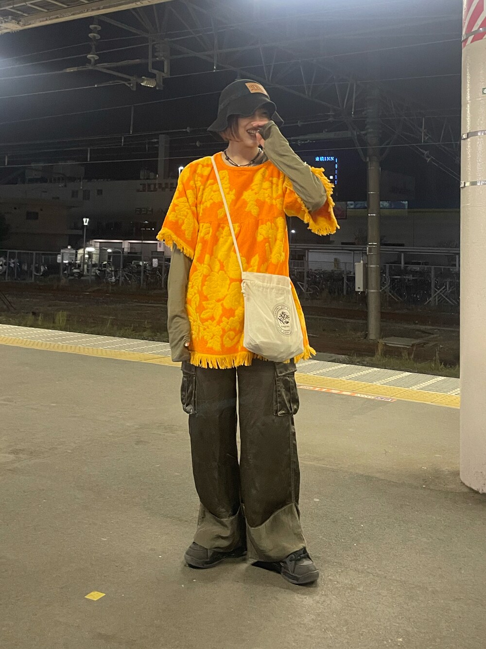 オレンジ系のワンピース/ドレス、グリーン系のトップス、グリーン系のパンツを着用したレディースの春コーディネートの1枚目の写真