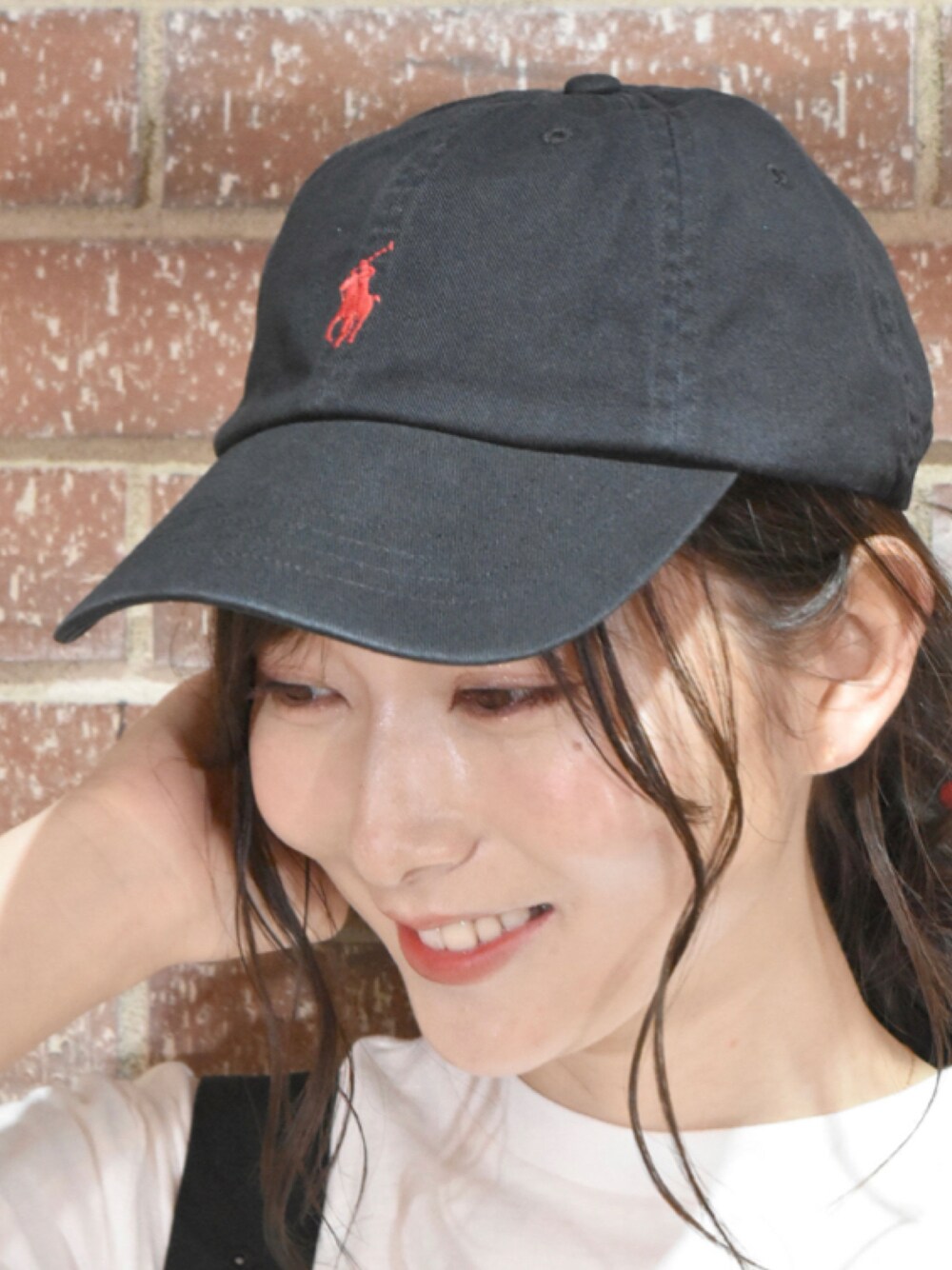 ブラック系のキャップを着用したレディースの夏コーディネートの1枚目の写真