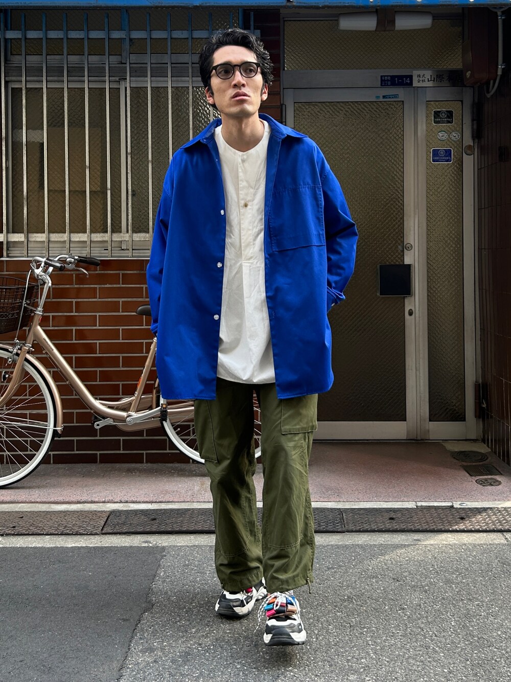 ブルー系のシャツ/ブラウス、グリーン系のカーゴパンツ、ブラック系のスニーカーを着用したメンズの春コーディネートの1枚目の写真