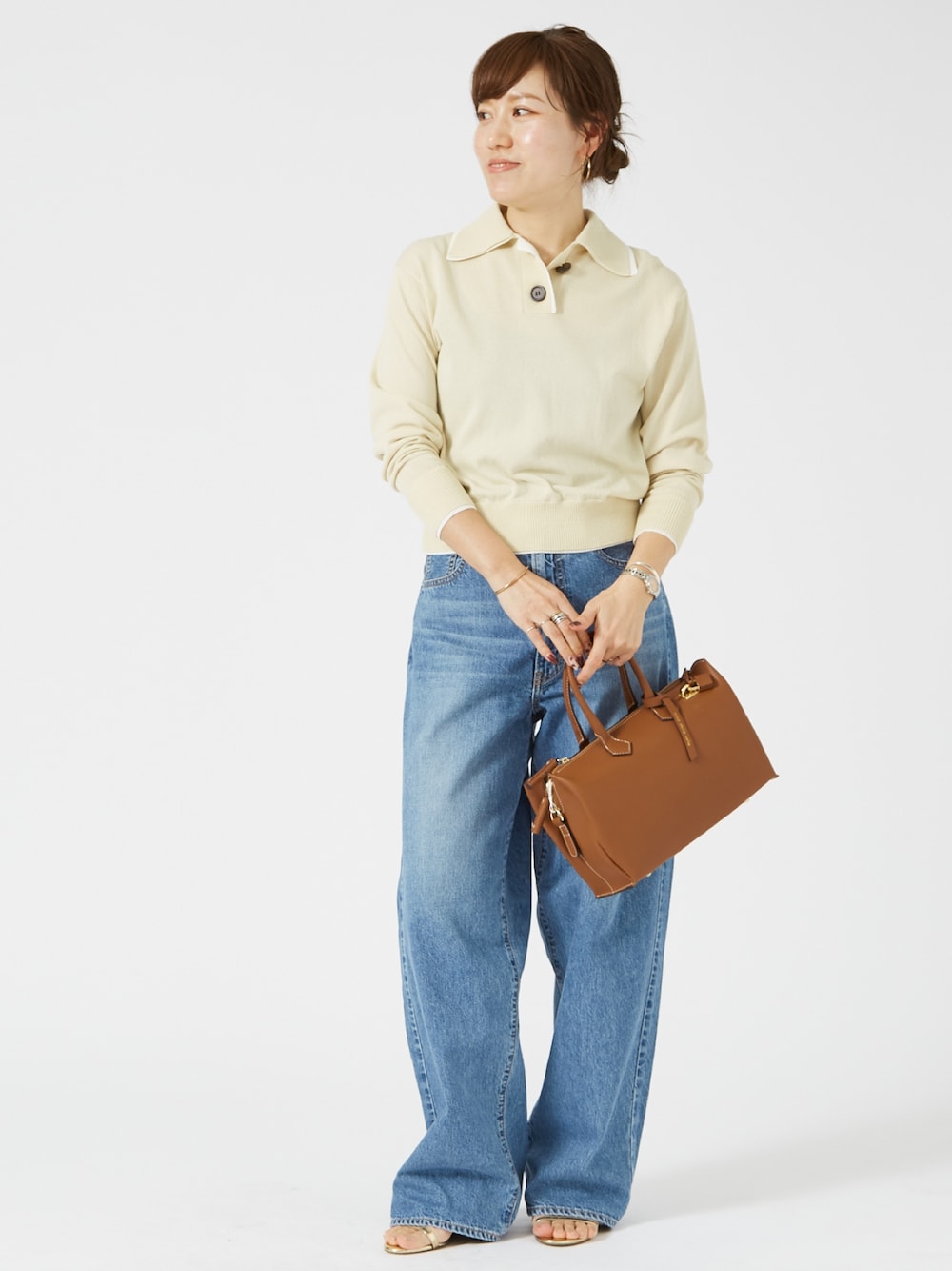 ブルー系のデニムパンツ、イエロー系のショルダーバッグ、ベージュ系のニット/セーターを着用したレディースの春コーディネートの1枚目の写真