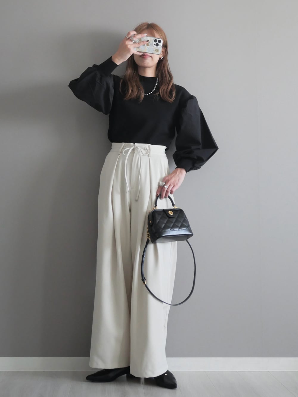 ブラック系のトートバッグ、ブラック系のニット/セーター、ブラック系のパンプスを着用したレディースの秋コーディネートの1枚目の写真