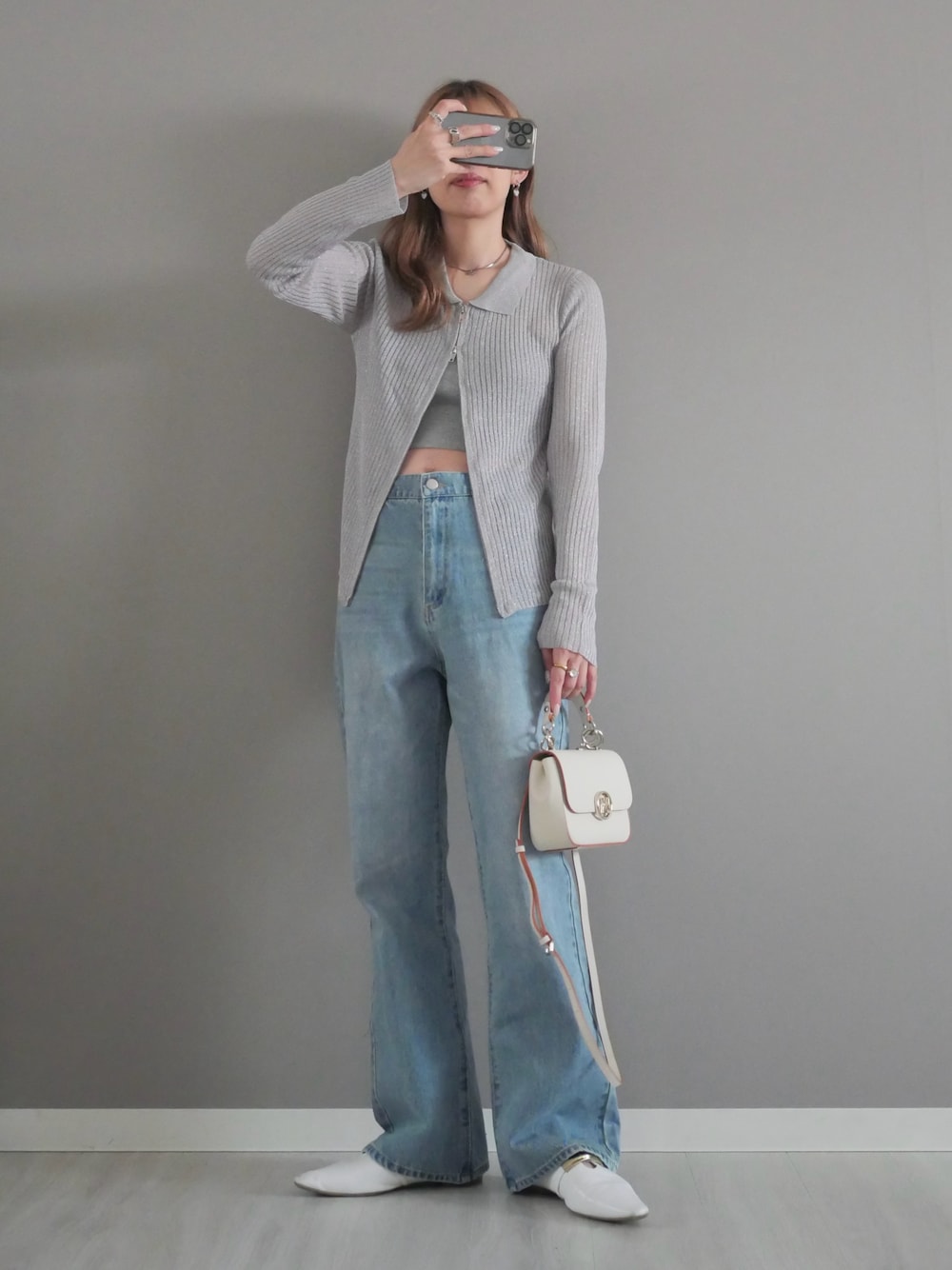 グレー系のカーディガン/ボレロ、ブルー系のデニムパンツ、ホワイト系のハンドバッグを着用したレディースの春コーディネートの1枚目の写真