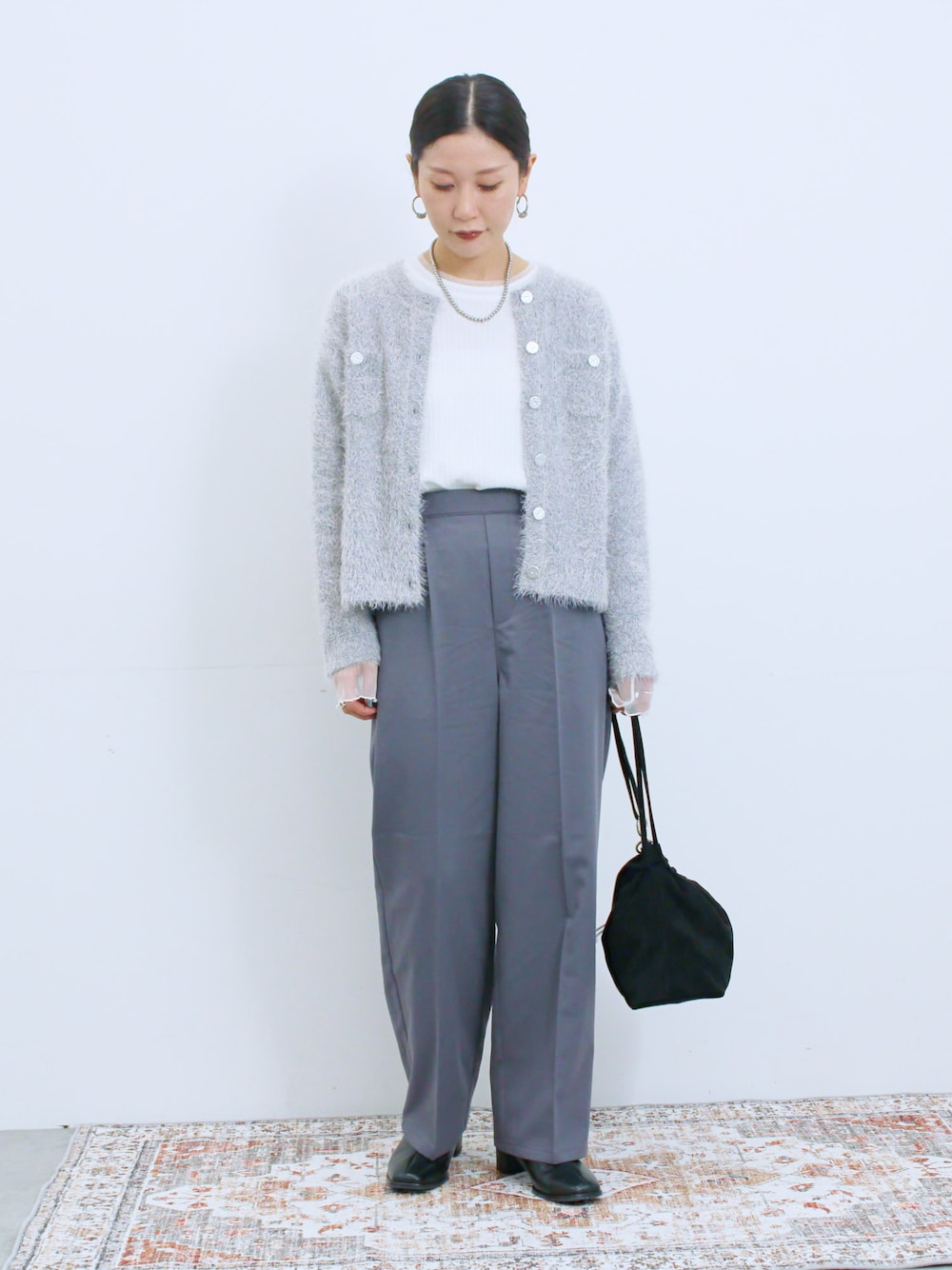 ブラック系のハンドバッグ、ブラック系のドレスシューズ、ホワイト系のTシャツ/カットソーを着用したレディースの冬コーディネートの1枚目の写真