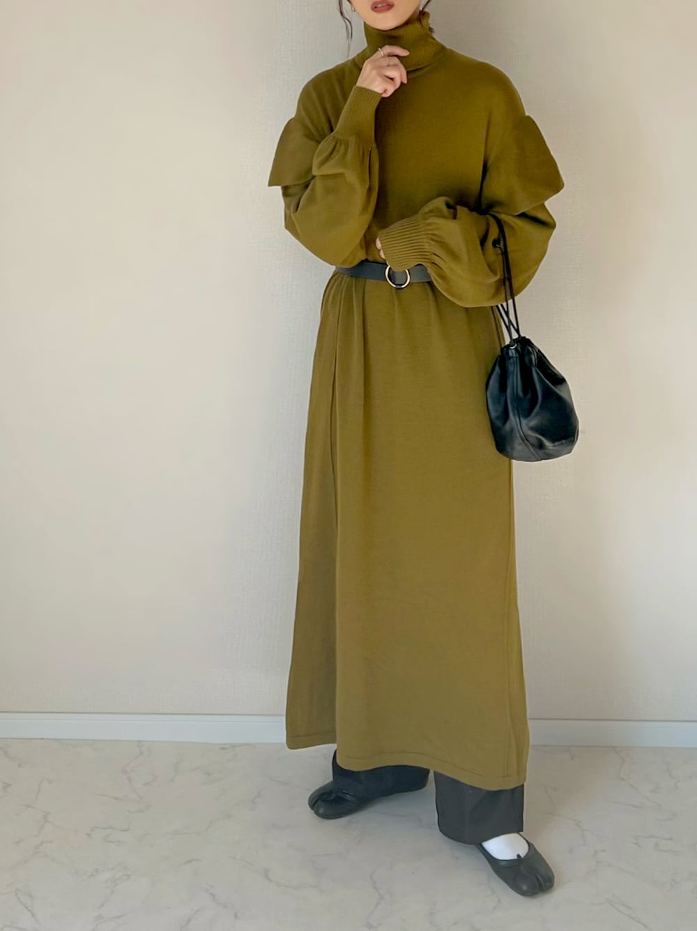 グリーン系のワンピース、ブラック系のハンドバッグを着用したレディースの秋コーディネートの1枚目の写真